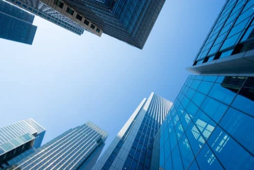 Glass office towers seen from street level against a clear blue sky