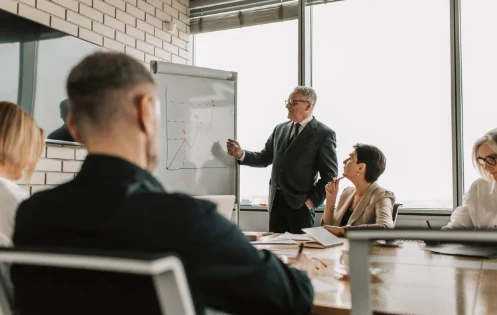 A presenter walking a leadership team through a growth chart in a meeting room